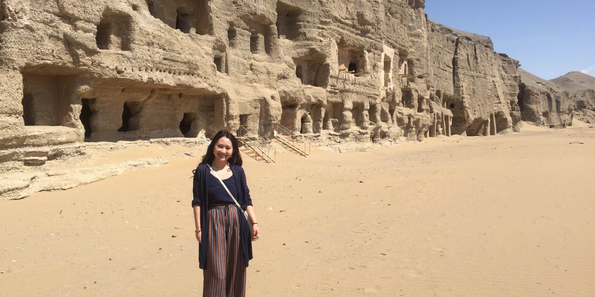 young dark haired woman smiling outside sandstone structures