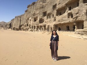 young dark haired woman smiling outside sandstone structures