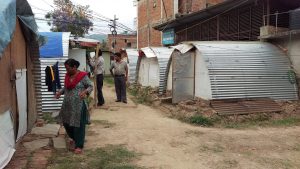 people walking among small structures roofed with corrugated metal