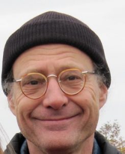 headshot of gray haired man with toque and glasses smiling