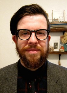 headshot of dark haired bearded man with glasses