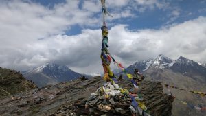 pillar atop mountain wrapped in prayer flags