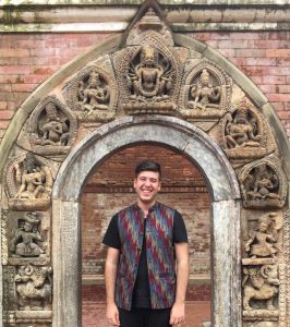 man smiling under carved buddhist gateway