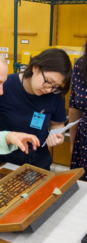 photo of young woman in glasses inspecting museum artifact