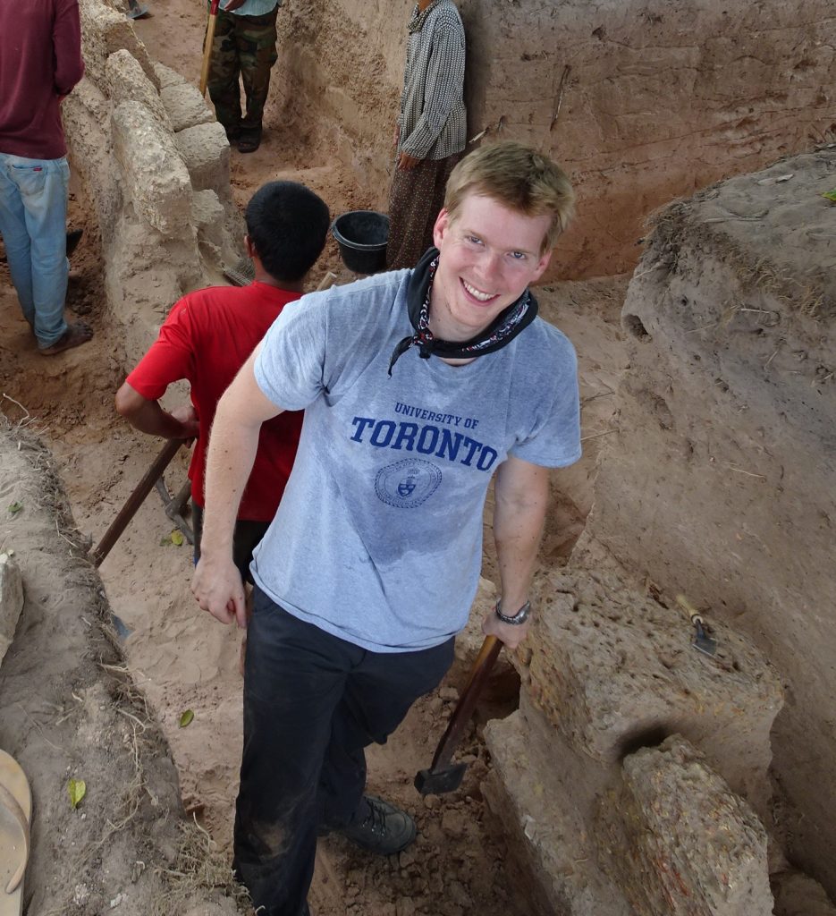young man looking up from excavation site and smiling