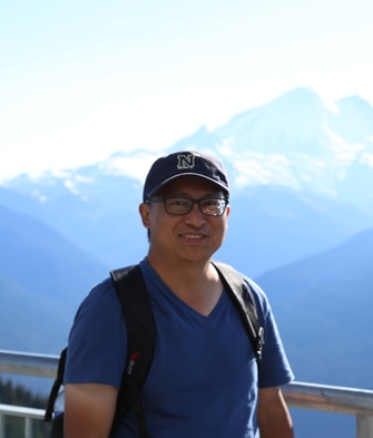 man with glasses and hat in front of mountain range