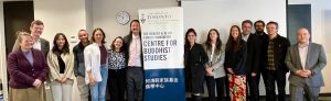 group of people in a line against the wall with Ho Centre for Buddhist Studies banner displayed in the middle